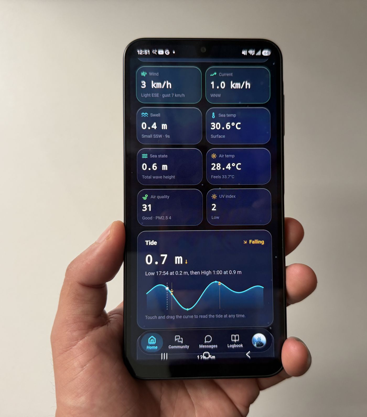 An Android phone showing Diving Standard's conditions screen with wind, current, swell, sea temperature, air temperature, UV and a tide curve